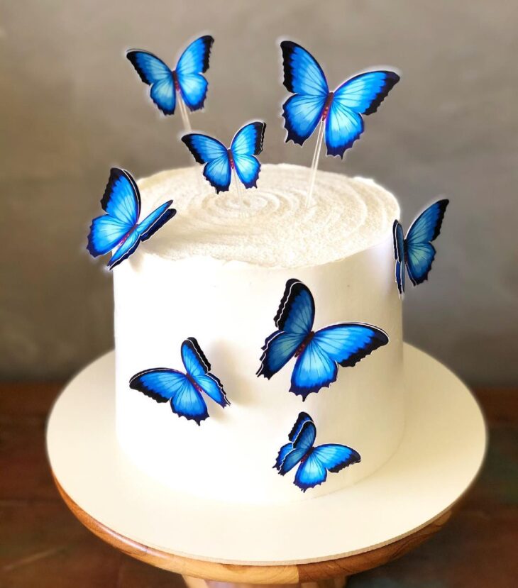 Bolo de aniversário branco decorado com borboletas azuis e